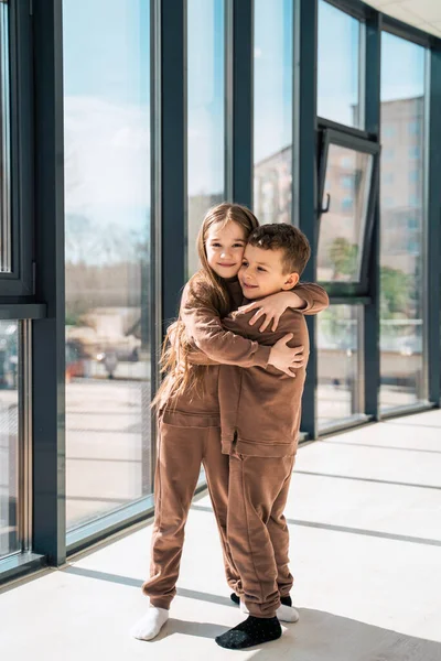 Cute brother and sister in the same clothes hugging - Stock Image