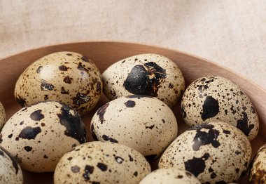 Yuvarlak ahşap kutuda bıldırcın yumurtalarının üst görüntüsü. Yiyecek arka planında monokrom.