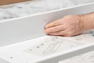 Evde, yerde bir ışık masası monte etmek. Adam tablo ayrıntılarını birleştirir