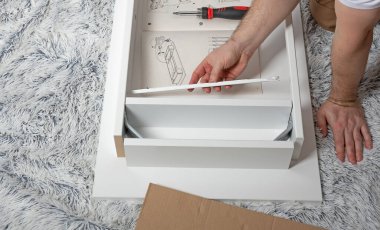 Evde, yerde bir ışık masası monte etmek. Adam tablo ayrıntılarını birleştirir