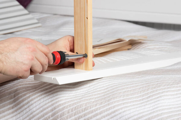 man collects white dressing table at home. Furniture assembly concept