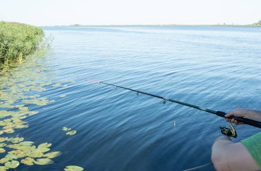 Adam nehirde balık tutuyor. Suyun üstündeki insanların elinde olta kamışı. Hobi ve eğlence konsepti.