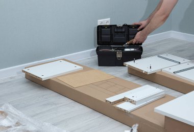 Mobilyaların taşınması ve montajı. Karton bir kutunun döşenmesi. Dairenin sahibine ait yeni mobilyaların montajı..