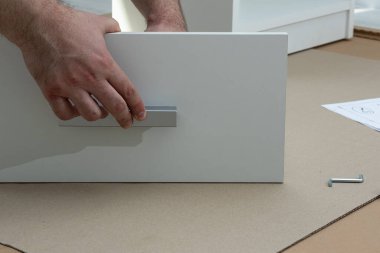 Yeni beyaz komodinin kutusunu monte etme işlemi. Taşınmak ve yeni mobilyalar almak dışında. Taşınmak ve mobilya montajı kavramı.