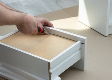 Yeni beyaz komodinin kutusunu monte etme işlemi. Taşınmak ve yeni mobilyalar almak dışında. Taşınmak ve mobilya montajı kavramı.