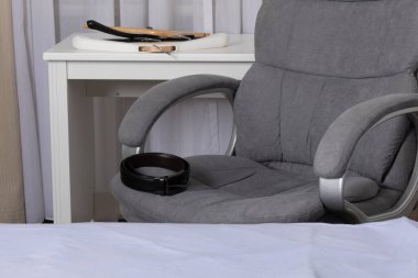 Ofis sandalyesi, kemer ve tepsiyle ev içi yatak odası düzeninde beyaz masanın üzerine.