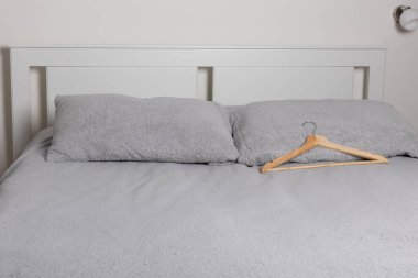 Rahat yatak, gri yatak ve beyaz yatak başlığında ahşap askı.