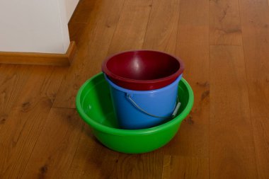 Ahşap zemindeki renkli plastik kovalar: kırmızı, mavi, yeşil konteynırlar