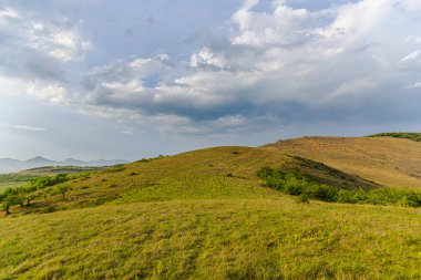 Yeşil çimenli ve mavi gökyüzü olan dağ manzarası