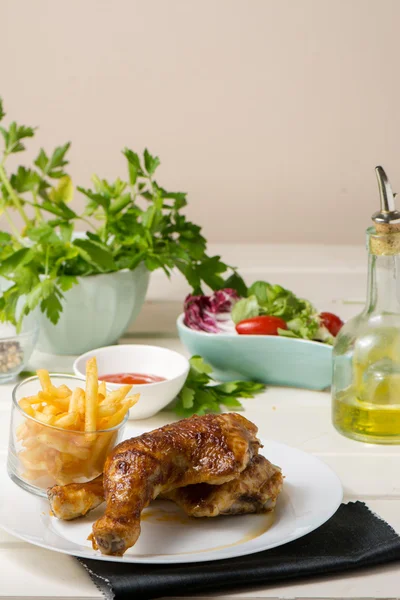 Muslos y papas fritas de pollo asado y ensalada de lechuga y tomate —  Fotos de Stock