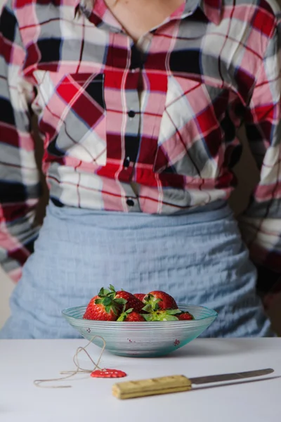 Tigela de morangos frescos, mulher em pé à mesa — Fotografia de Stock