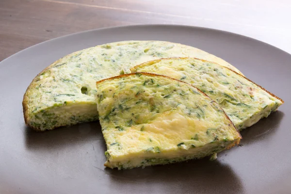 Tortilla con espinacas y calabacín con queso derretido en pla marrón — Foto de Stock