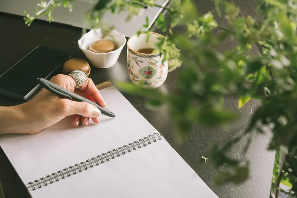 Kvinna händer skriver en penna i en anteckningsbok, tangentbord — Stockfoto