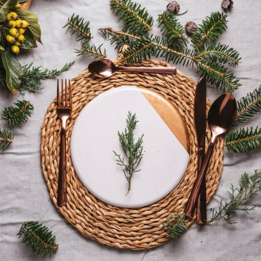 Noel sofrasında çelenk, çam dalı ve altın çatal bıçak seti var. Tatil yemeği.