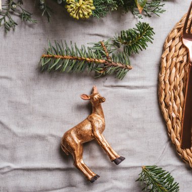 Tahta arka planda, doğal dallarla çevrili tabakta tatil yeri dekorasyonu ve oyuncak altın ren geyiği süslemesi. Xmas yer dekorasyonu için Noel dekorasyonu.