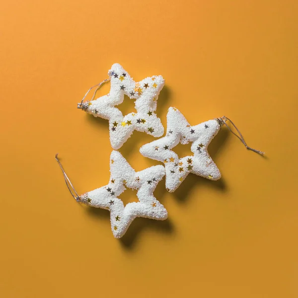 Three bright white Christmas stars on pastel background, minimal concept of Christmas and New Year. Minimalist decoration from above.