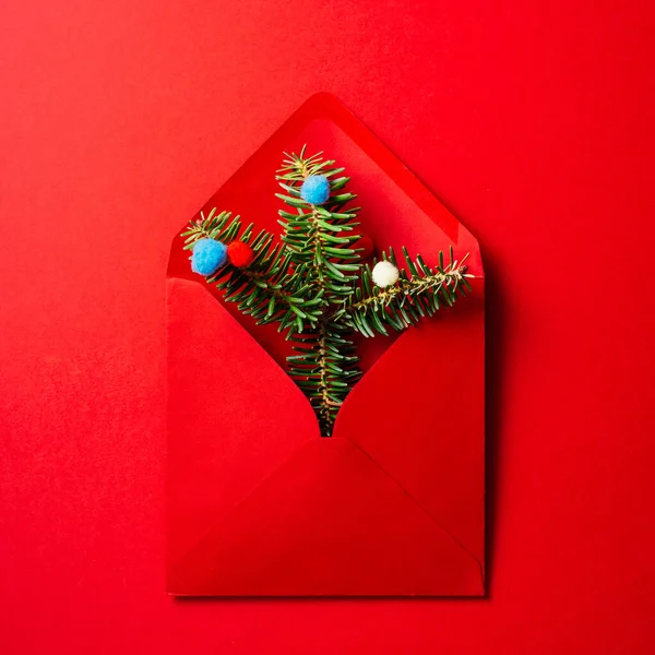 Kırmızı zemin üzerinde köknar ağacı dalları ve takılar olan kırmızı zarf