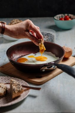 Ekmeği çırpılmış yumurtaya, tavaya bandırır. Brunch malzemeleriyle çevrilidir.
