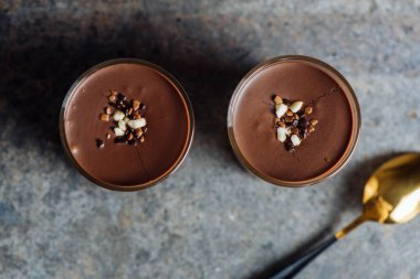 Çikolatalı tatlı, vanilyalı krema, bisküvi ve karamel bir bardakta, kırsal bir dokuda. Yukarıdan Hiç kimse 