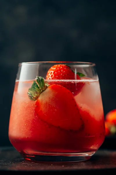 美味的草莓鸡尾酒 新鲜的夏季鸡尾酒 带有天然草莓和冰块 一杯草莓苏打水在漆黑的背景下饮用 — 图库照片