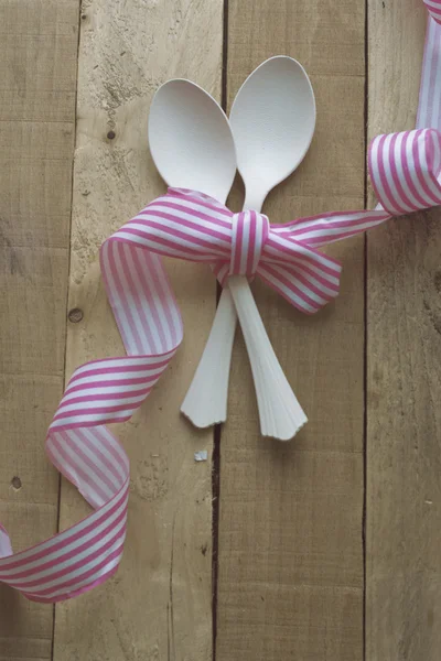 Cucchiai bianchi vintage, nastro rosa su fondo di legno — Foto Stock