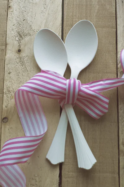 Vintage white spoons, pink ribbon on wooden background — Stock Photo, Image