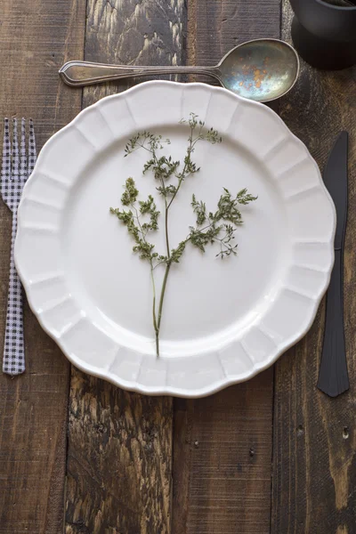 Piatto bianco, coltello e forchetta su vecchio tavolo di legno — Foto Stock