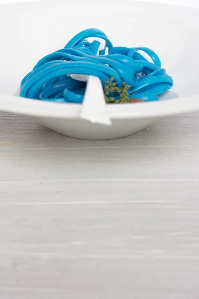 Blue spaghetti, black place setting — Stock Photo, Image