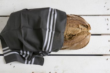 rustic bread, wrapped in striped fabric on white wooden backgrou clipart