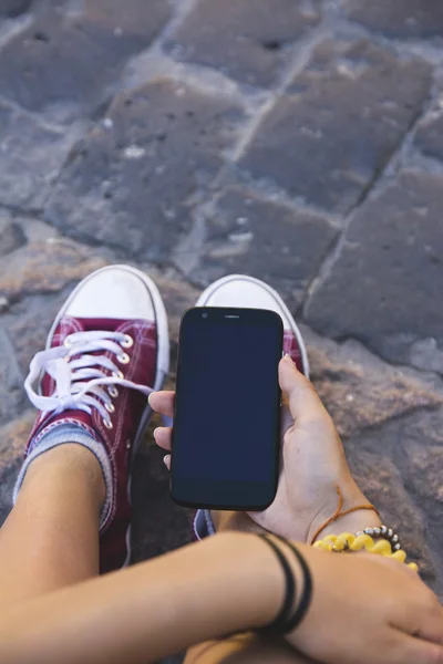 Tiener zitten met mobiele telefoon in de hand — Stockfoto