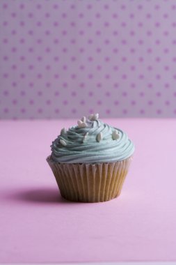 Krem şanti ve kalp şeker pembe nokta üzerinde mavi cupcake