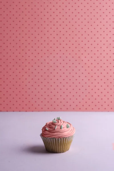 Roze cupcake met slagroom en hart hagelslag op gestippeld — Stockfoto