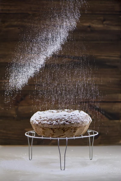 Versare lo zucchero a velo sulla torta fatta in casa rotonda — Foto Stock