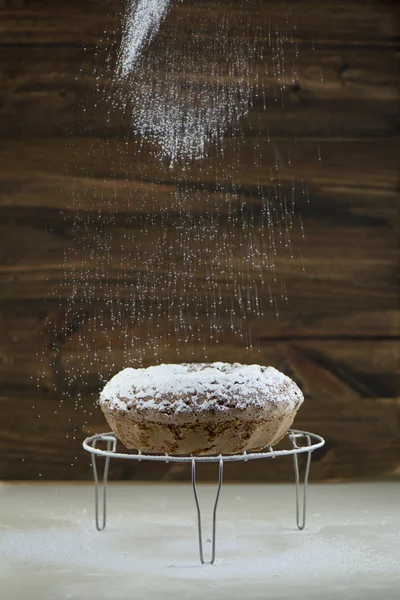 Verser le sucre en poudre sur le gâteau rond fait maison — Photo