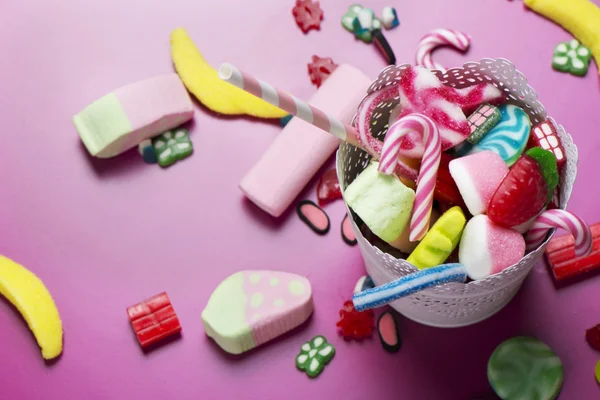 Pembe arka plan üzerinde renkli şeker karışık çocuklar tatil