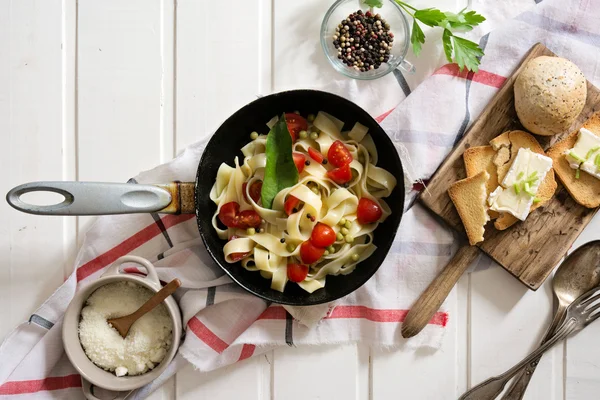Tagliatelle Pasta with cherry tomatoes in a pan  white wooden ta — Stock Photo, Image
