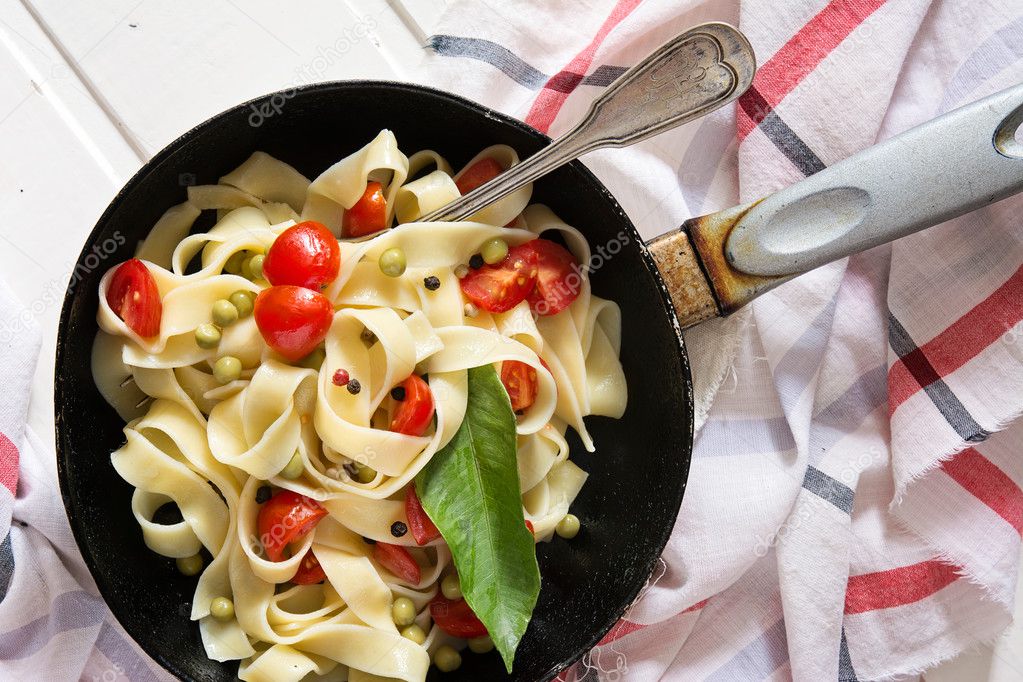 Tagliatelle Pasta with cherry tomatoes in a pan  white wooden ta