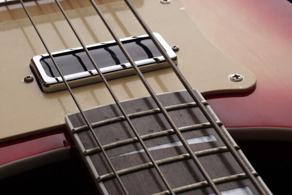 Closeup of four-string electric guitar. Detail, selective focus.