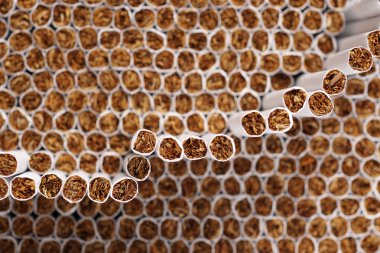 Arka plan veya doku olarak yığılmış sigara tam çerçeve. Bir sigaranın ucuna seçici odak