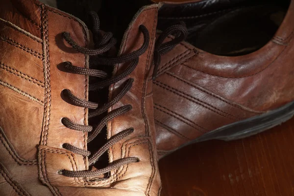 Część starych butów ze sznurowadłami na podłogi drewniane — Zdjęcie stockowe