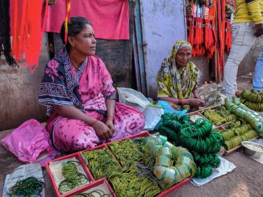 Tuljapur, İndiana - 19 Aralık 2019; 40-50 yaş aralığında iki Hintli kadın sari giyip Tuljapur, Maharashtra 'daki tapınak alanının dışında güzel yeşil cam bilezikler satarken çekilmiş.