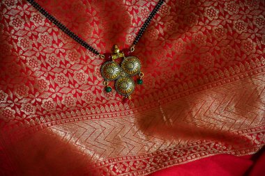 Güzel kırmızı ve altın sarısı arka planda siyah inci zincirli güzel altın renkli Mangalsutra tablosu..