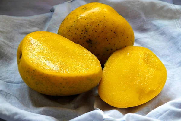 Beyaz arka planda iki taze, olgun sarı mango resmi..