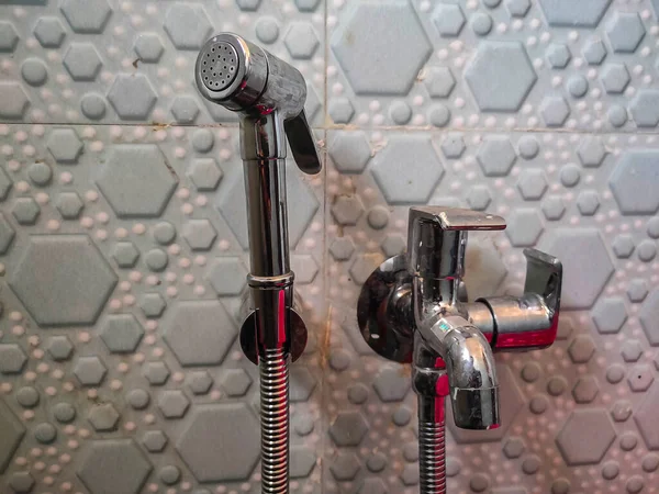 Kolhapur, Maharashtra, Hindistan 'da gümüş bide duşu ya da duvara musluk takılı serseri silah kullanan el fotoğrafı.