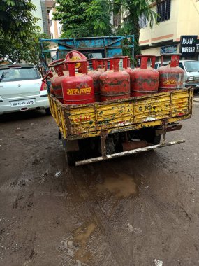 Kolhapur, Hindistan - 24 Ağustos 2021; Paslı, sarı, küçük tempo ya da yerli pişirme gazı silindiri ya da LPG gaz silindiri taşıyan minibüsün arka görünümü. Hindistan 'da yağmur mevsiminde yakalanmış..