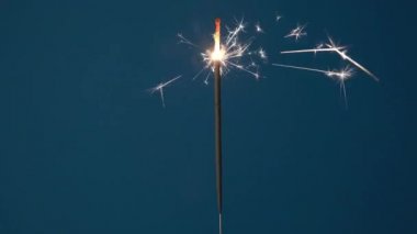 Noel ya da Mutlu Yıllar konsepti. Fotokopi alanı olan mavi bir arkaplanda yanan parlak maytap sancağını kapat. 4k çözünürlük videosu