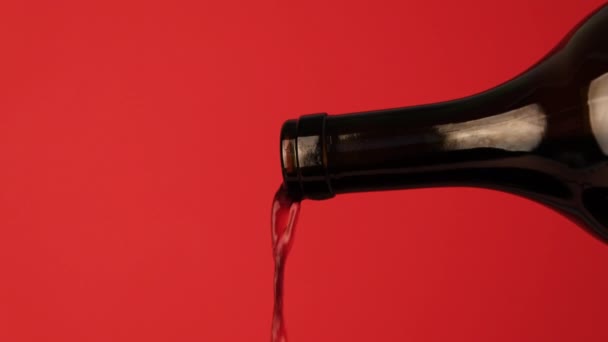 ピンクワインを注ぐワインボトルの首を閉じます 赤ワインは赤を背景に濃いガラス製の瓶から注ぐ — ストック動画