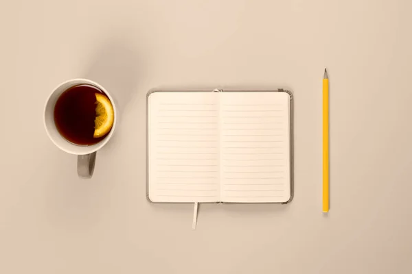 Tea cup and fancy notebook with empty or blank page on desk from above, planning and design concept. Top view, flat lay, copy space. Mock up toned in trendy 2021 color.
