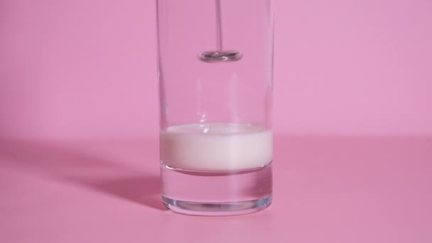 在粉色背景的透明玻璃杯中 用便携式手部乳霜对有机牛奶进行抽打 慢动作 家用拿铁或奶昔的视频说明 第2步 — 图库视频影像