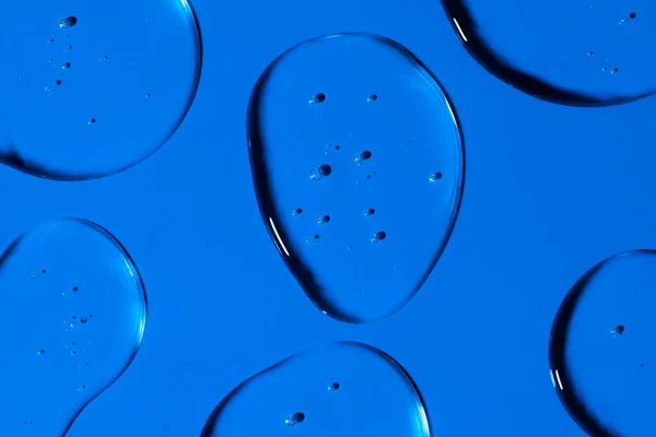 透明凝胶下降形成背景或模式 蓝色背景下的凝胶滴病毒防护或化妆品概念 — 图库照片